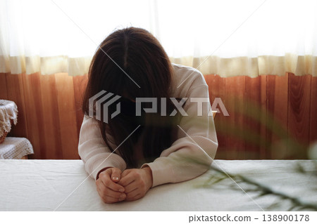 一位頭髮蓬亂、身穿家居服的女子無精打采地低著頭。 138900178