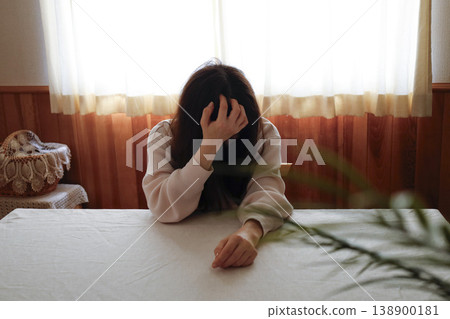 A woman, with her hair unkempt and still in her loungewear, hangs her head listlessly. A woman, with her hair unkempt and still in her loungewear, hangs her head listlessly. 138900181