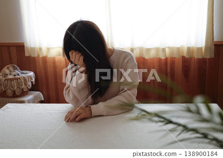 A woman, with her hair unkempt and still in her loungewear, hangs her head listlessly. A woman, with her hair unkempt and still in her loungewear, hangs her head listlessly. 138900184