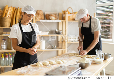 Elderly man and woman cutting dough and forming pieces Elderly man and woman cutting dough and forming pieces 138900217