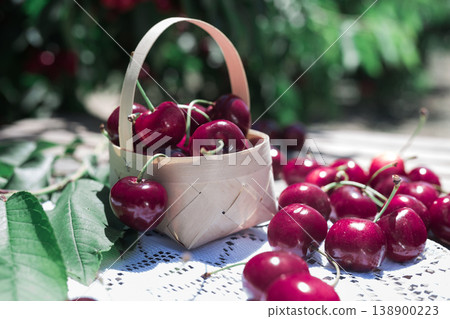 still life of cherries in wicker basket on table in garden 138900223