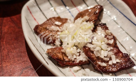 close up of grilled slices of beef ox tongue with onion on top and copyspace  138900704
