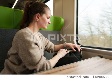 Woman organizing bag and belongings during train trip Woman organizing bag and belongings during train trip 138900729