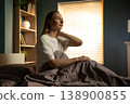 Woman wakes in morning, sits in bed rubbing her neck, wincing from stiffness and ache after poor sleep or bad posture, showing tension and morning discomfort 138900855
