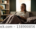 Woman reading a book in bed under a cozy blanket, enjoying a peaceful morning at home, relaxed and thoughtful during a quiet self care moment of leisure and comfort 138900856