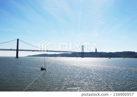 Sailboat Sailing Under 25th of April Bridge on a Sunny Day, Portugal 138900957