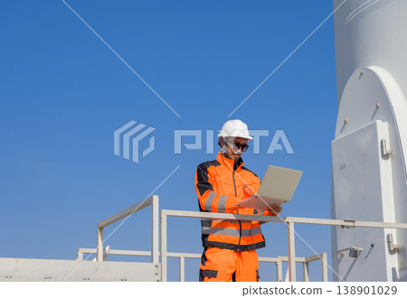 Wind turbine technician conducting digital performance inspection on elevated platform at renewable energy facility 138901029