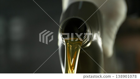 Close-up of motor oil pouring from a plastic container. Golden viscous liquid with bubbles flowing smoothly, automotive maintenance concept with shallow depth of field. Close-up of motor oil pouring from a plastic container. Golden viscous liquid with bubbles flowing smoothly, automotive maintenance concept with shallow depth of field. 138901078