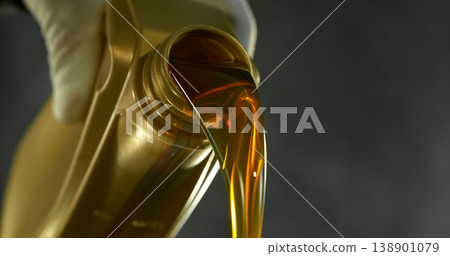 Close-up of motor oil pouring from a plastic container. Golden viscous liquid with bubbles flowing smoothly, automotive maintenance concept with shallow depth of field. Close-up of motor oil pouring from a plastic container. Golden viscous liquid with bubbles flowing smoothly, automotive maintenance concept with shallow depth of field. 138901079