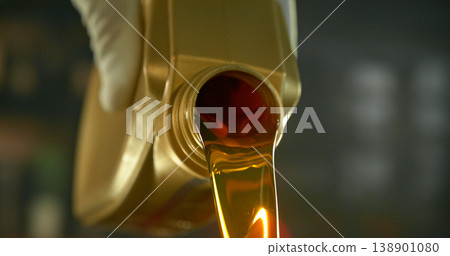 Close-up of motor oil pouring from a plastic container. Golden viscous liquid with bubbles flowing smoothly, automotive maintenance concept with shallow depth of field. Close-up of motor oil pouring from a plastic container. Golden viscous liquid with bubbles flowing smoothly, automotive maintenance concept with shallow depth of field. 138901080