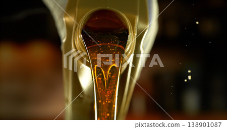 Close-up of motor oil pouring from a plastic container. Golden viscous liquid with bubbles flowing smoothly, automotive maintenance concept with shallow depth of field. Close-up of motor oil pouring from a plastic container. Golden viscous liquid with bubbles flowing smoothly, automotive maintenance concept with shallow depth of field. 138901087