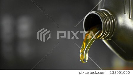 Close-up of motor oil pouring from a plastic container. Golden viscous liquid with bubbles flowing smoothly, automotive maintenance concept with shallow depth of field. Close-up of motor oil pouring from a plastic container. Golden viscous liquid with bubbles flowing smoothly, automotive maintenance concept with shallow depth of field. 138901090