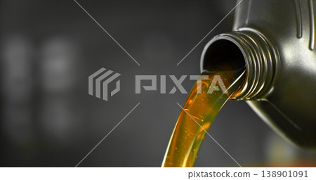Close-up of motor oil pouring from a plastic container. Golden viscous liquid with bubbles flowing smoothly, automotive maintenance concept with shallow depth of field. Close-up of motor oil pouring from a plastic container. Golden viscous liquid with bubbles flowing smoothly, automotive maintenance concept with shallow depth of field. 138901091