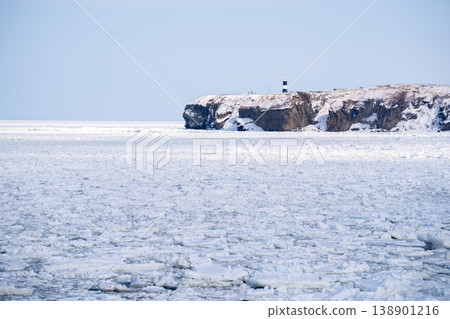 Cliffs and a lighthouse on the Sea of Okhotsk, enveloped in drift ice (Hokkaido, winter) 138901216