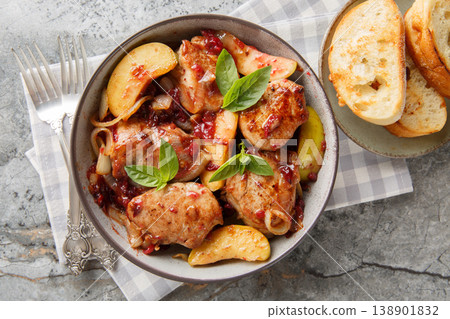 Close-up of seared and then braised pork tenderloin with caramelized onions, cranberry sauce and green apples in a bowl. Horizontal top view 138901832