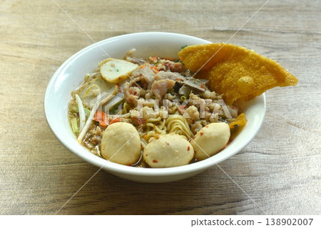 Chinese egg yellow noodles topping chop pork and meatball with crispy fried dumpling paste in spicy tom yum soup on bowl 138902007