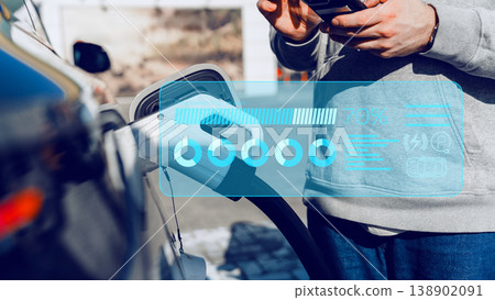 Charging an electric car at a public station while checking the status on a mobile device Charging an electric car at a public station while checking the status on a mobile device 138902091