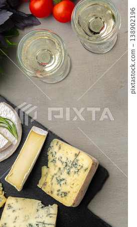 Cheese and wine setup with tomatoes and herbs on a gray table Cheese and wine setup with tomatoes and herbs on a gray table 138902196