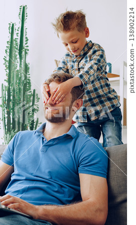 Child plays with adult while sitting on couch in living room during daytime at home 138902214