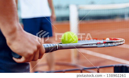 Tennis player prepares to serve a ball on a clay court during afternoon practice session Tennis player prepares to serve a ball on a clay court during afternoon practice session 138902261