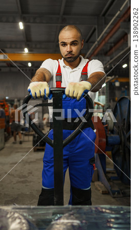 Worker moving equipment in warehouse using pallet jack during day shift Worker moving equipment in warehouse using pallet jack during day shift 138902262