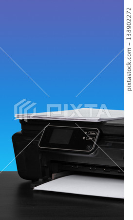 Printer with paper on a table against a blue background during daylight Printer with paper on a table against a blue background during daylight 138902272