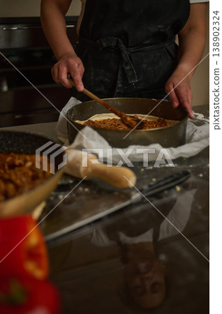 Home Baker Spreading Savory Filling Into Pastry Tin In Rustic Kitchen Home Baker Spreading Savory Filling Into Pastry Tin In Rustic Kitchen 138902324