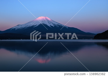 The breathtaking view of the inverted red Mt. Fuji reflected in Lake Yamanaka in the early morning. The breathtaking view of the inverted red Mt. Fuji reflected in Lake Yamanaka in the early morning. 138902382