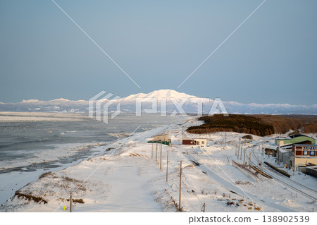 Hokkaido in winter: drift ice on the coast, buildings, and snow-covered mountains. Hokkaido's rugged coastline, the Sea of Japan, and the Pacific Ocean. Rough waves and towering cliffs continue. Hokkaido in winter: drift ice on the coast, buildings, and snow-covered mountains. Hokkaido's rugged coastline, the Sea of Japan, and the Pacific Ocean. Rough waves and towering cliffs continue. 138902539