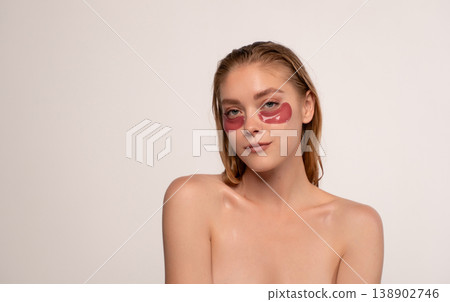 Young woman applying red hydrogel eye patches for under eye skincare, moisturizing and reducing puffiness Young woman applying red hydrogel eye patches for under eye skincare, moisturizing and reducing puffiness 138902746