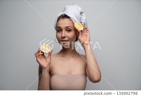 Woman with a towel turban holding fresh lemon halves for natural skincare, wellness, beauty, and organic cosmetic treatment, promoting healthy lifestyle Woman with a towel turban holding fresh lemon halves for natural skincare, wellness, beauty, and organic cosmetic treatment, promoting healthy lifestyle 138902798
