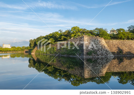 The stone walls of Osaka Castle and the fresh greenery reflected in the moat 138902991
