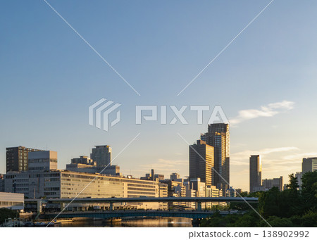 A cluster of buildings and a highway spread out under a blue sky. A cluster of buildings and a highway spread out under a blue sky. 138902992