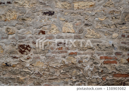 Textured stone wall with various colors and patterns, aged surface in urban setting Textured stone wall with various colors and patterns, aged surface in urban setting 138903082