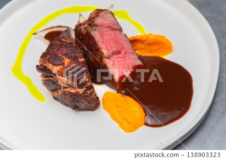 Grilled beef steak served with sauce and colorful vegetable puree on plate 138903323