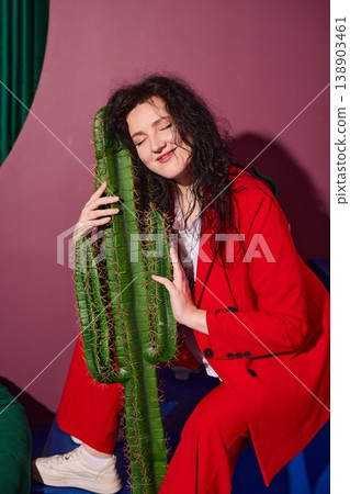 Tranquil individual leaning gently against cactus inside studio Tranquil individual leaning gently against cactus inside studio 138903461