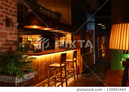 Cozy bar ambiance. Inviting lounge with warm lighting and rustic decor Cozy bar ambiance. Inviting lounge with warm lighting and rustic decor 138903469