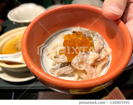 Shirataki noodles and lotus root salad with mayonnaise dressing - served in a small bowl topped with salmon roe. Shirataki noodles and lotus root salad with mayonnaise dressing - served in a small bowl topped with salmon roe. 138903491
