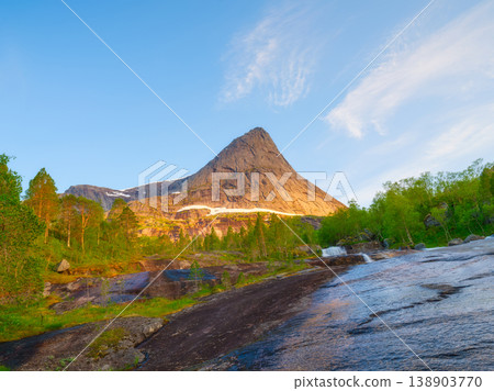 Scenic waterfall flowing from a mountain peak in Norway. Midnight sun. Scenic waterfall flowing from a mountain peak in Norway. Midnight sun. 138903770