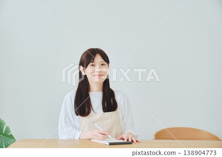 A woman is taking notes on the menu; a scene depicting meal preparation and daily planning. A woman is taking notes on the menu; a scene depicting meal preparation and daily planning. 138904773