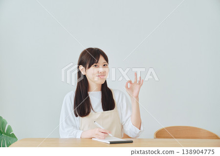 A woman is taking notes on the menu; a scene depicting meal preparation and daily planning. A woman is taking notes on the menu; a scene depicting meal preparation and daily planning. 138904775