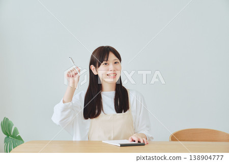 A woman is taking notes on the menu; a scene depicting meal preparation and daily planning. 138904777