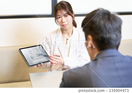 A female industrial physician explains to employees while showing them data on a tablet. 138904973