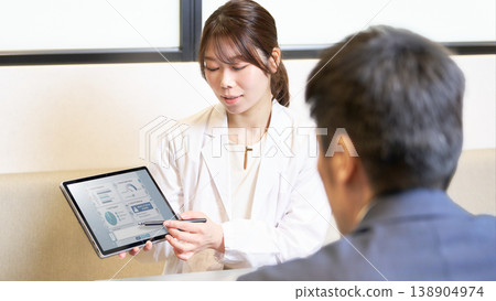 A female industrial physician explains to employees while showing them data on a tablet. 138904974