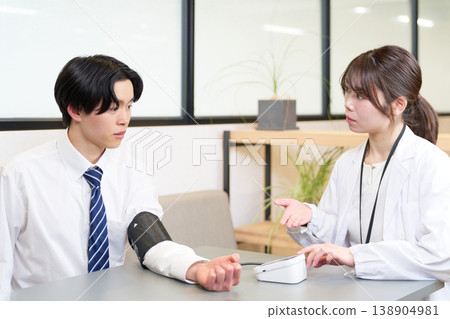 一位年輕的商人正在測量血壓。 一位年輕的商人正在測量血壓。 138904981