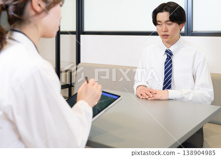 A young male employee consults with an industrial physician about his worries and health problems during an individual consultation. A young male employee consults with an industrial physician about his worries and health problems during an individual consultation. 138904985