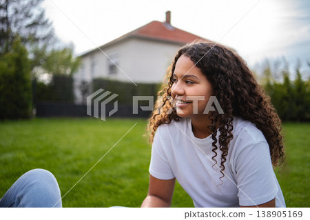 Smiling teenager relaxing in backyard looking away 138905169