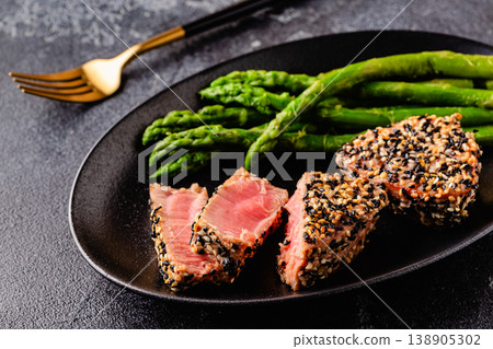 Tuna steak fried in sesame seeds served with asparagus. 138905302