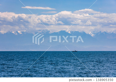 Boat sailing on serene water with mountains in background 138905350