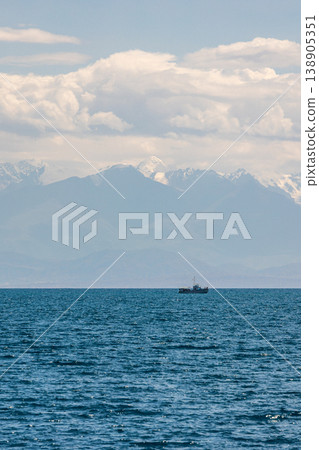 People cruising on boat in calm Issyk-Kul lake with mountains on the horizon People cruising on boat in calm Issyk-Kul lake with mountains on the horizon 138905351